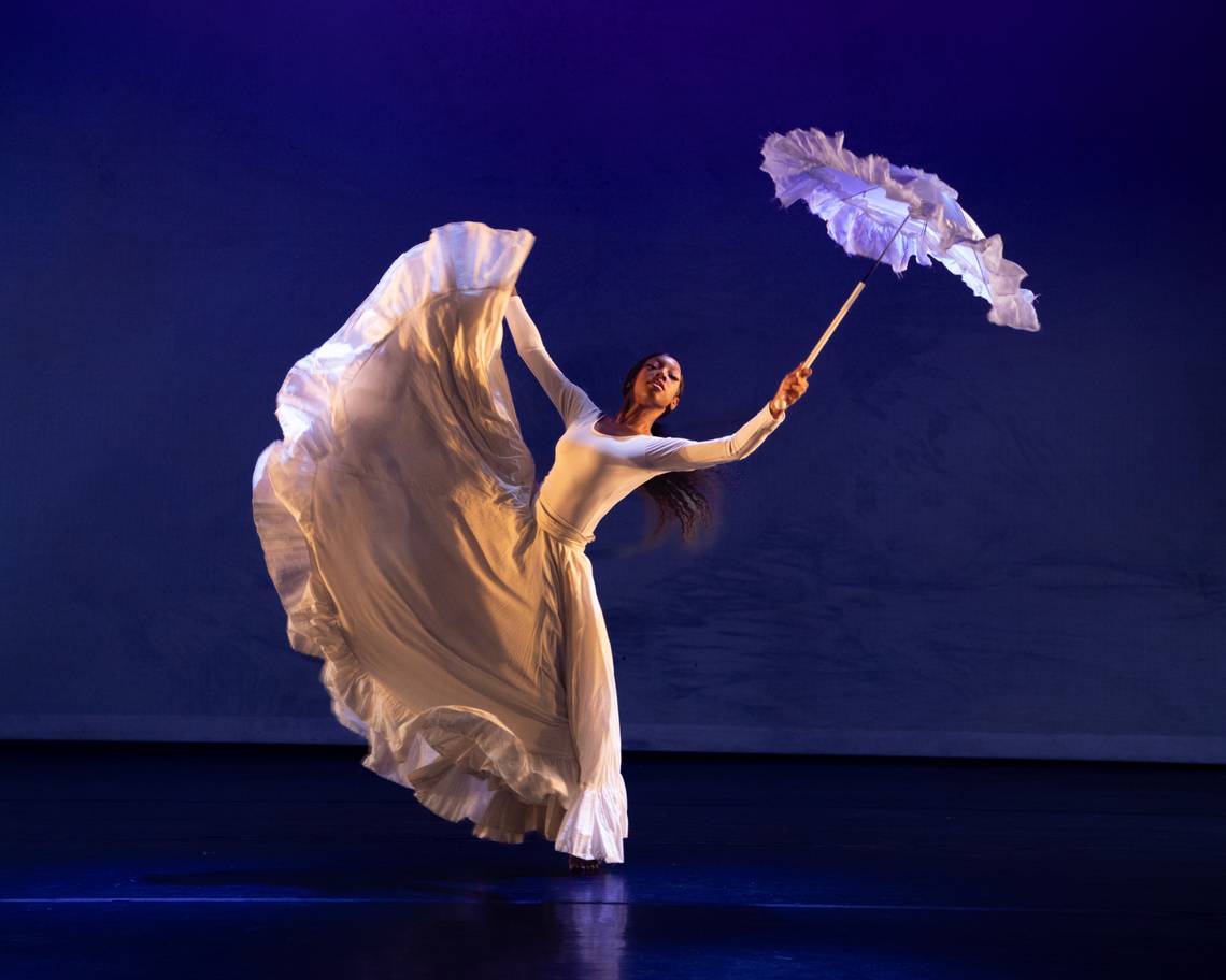a dancer on stage holding an umbrella